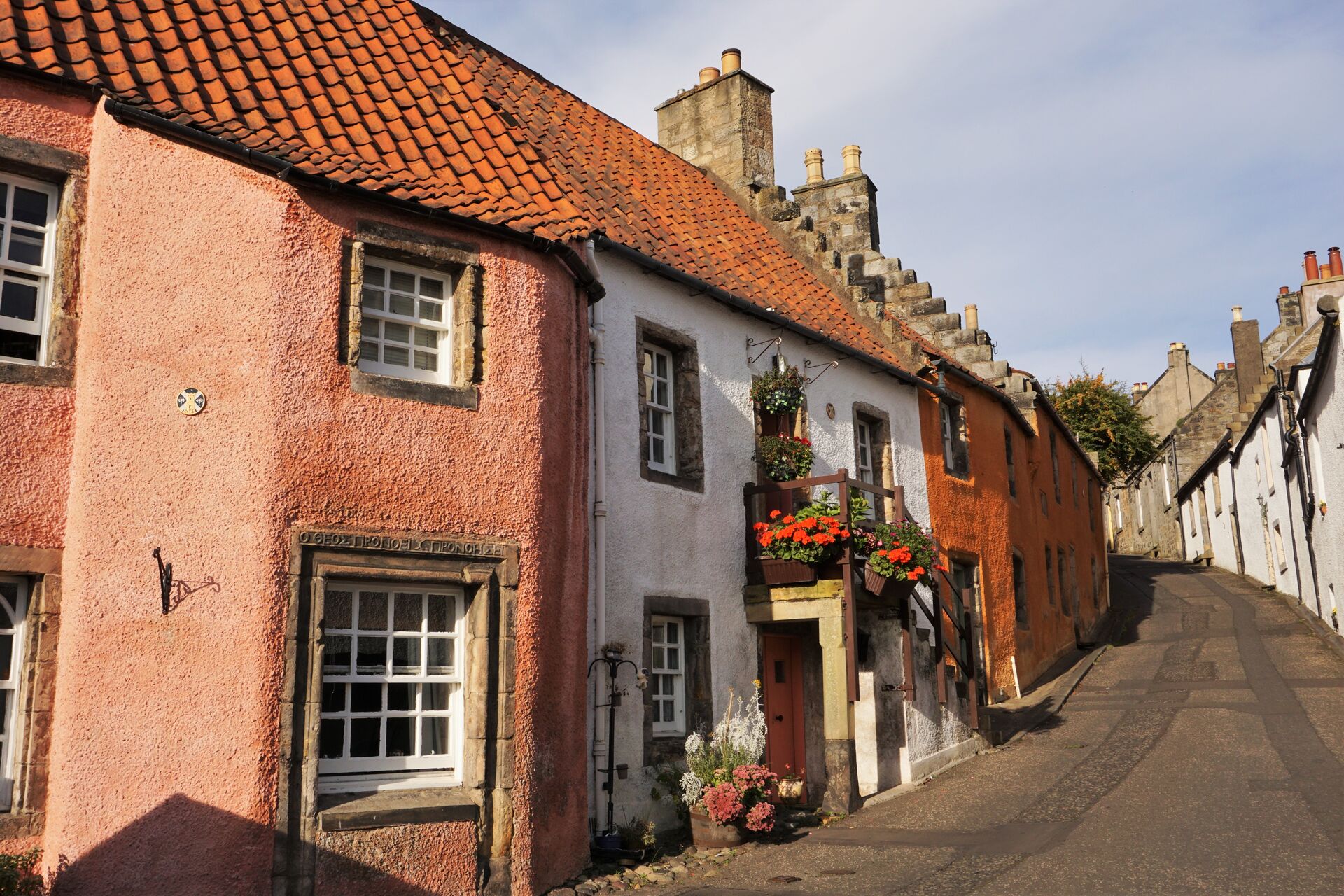 Narrow alley in quaint Culross village with colourful housefronts and flower pots in the windows